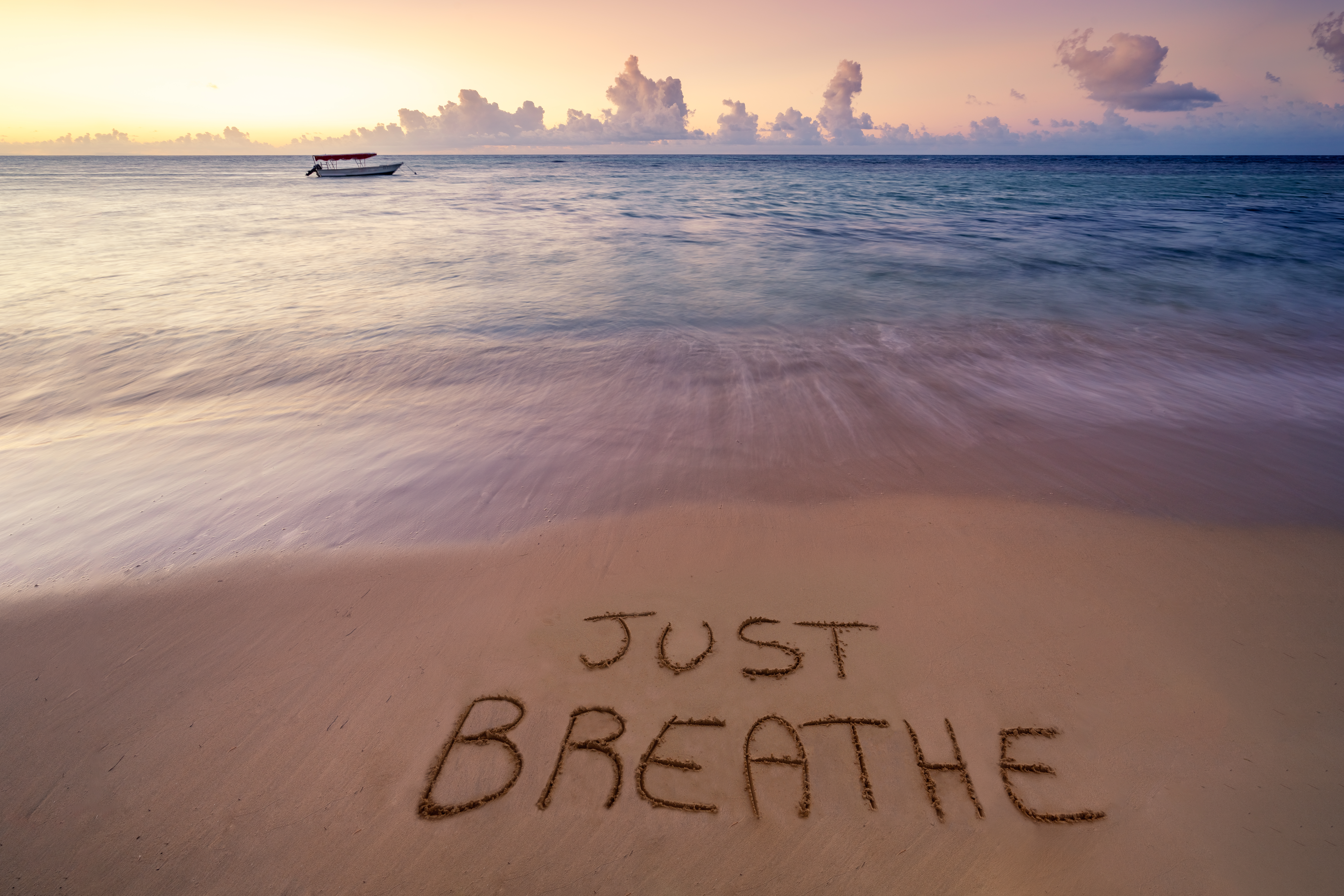 a beach at sunset with 'Just Breathe' drawn in the sand