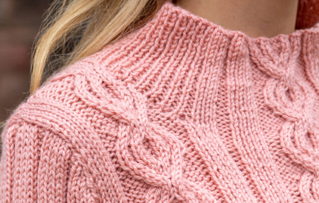 Close up of salmon pink cable knit sweater shoulder and collar