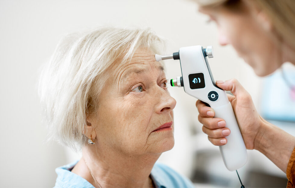 Elderly white haired woman having an eye checked by an optometrist