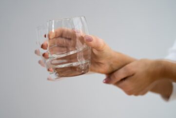 A shaking hand holding a glass of water with obvious shakes