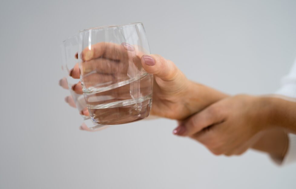 A shaking hand holding a glass of water with obvious shakes