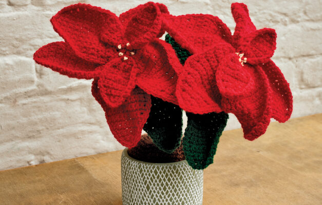 Crochet red poinsettia in a vase on wooden table