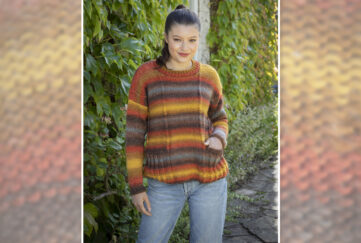 Model wearing easy knit sweater with blue jeans and brown hair in front of hedge