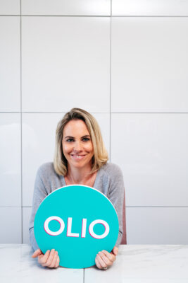 Headshot of Tessa Clarke of OLIO, holding an OLIO logo sign