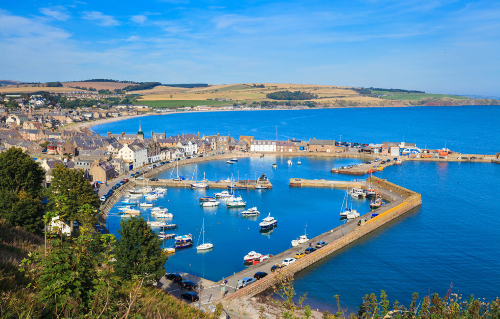An aerial view of Stonehaven harbour with bright blue waters on a sunny day