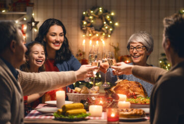 A family gathered around the Christmas table clinking their drink glasses