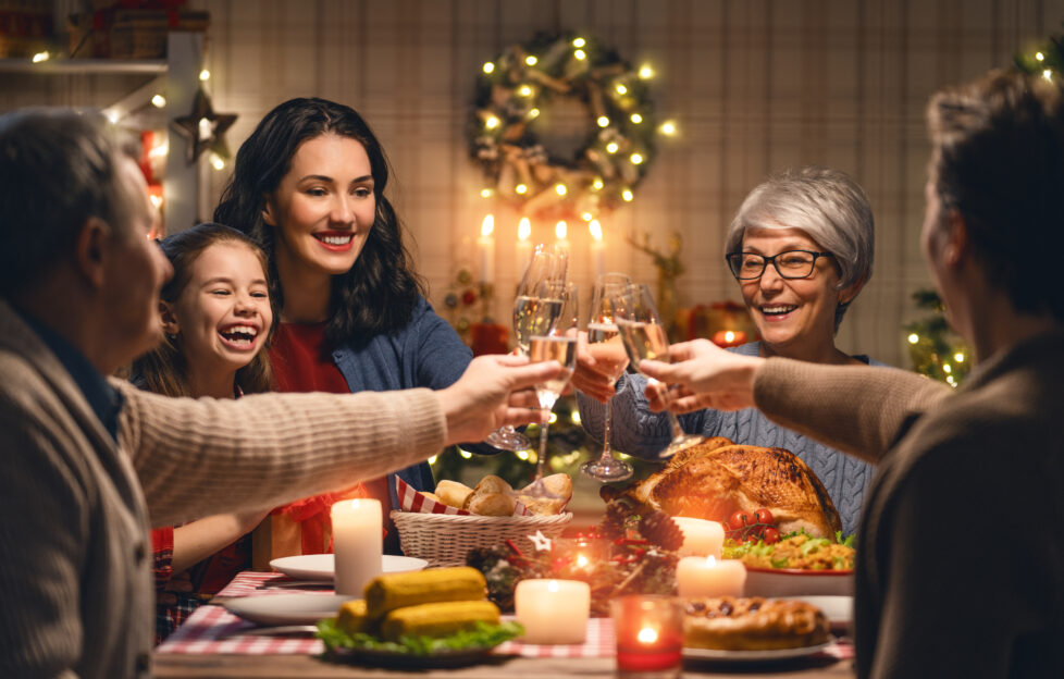 A family gathered around the Christmas table clinking their drink glasses