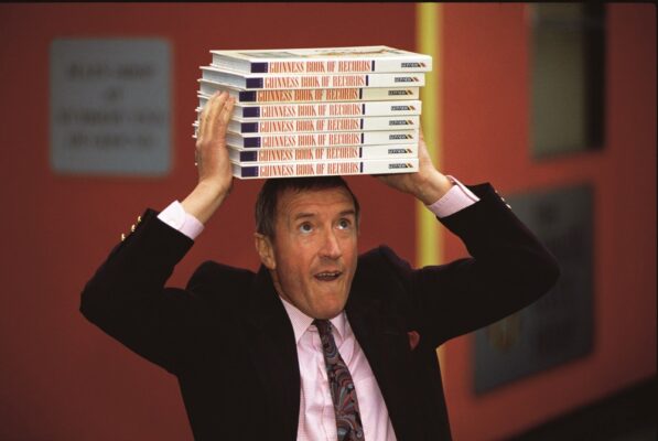 Roy Castle of "Record Breakers" balancing a pile of Guinness Book of Records on his head.