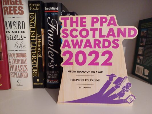 The physical award for Media Brand Of The Year from The PPA Scotland Awards 2022 awarded to The People's Friend of DC Thomson sitting on a bookshelf