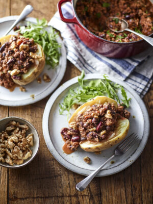 Chilli California Walnut jacket potatoes on a plate with pot of mince and bowl of walnuts 