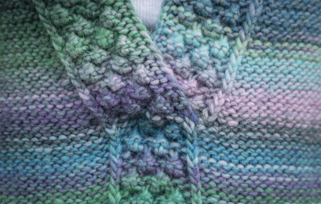 Close up of knitted overtop v neck with detailed knitting in cool toned yarn