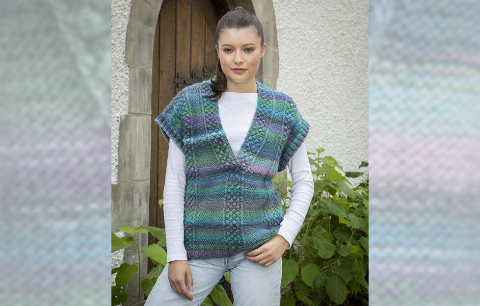 Brown haired woman model wearing bright cool toned knitted overtop with white long sleeved shirt underneath