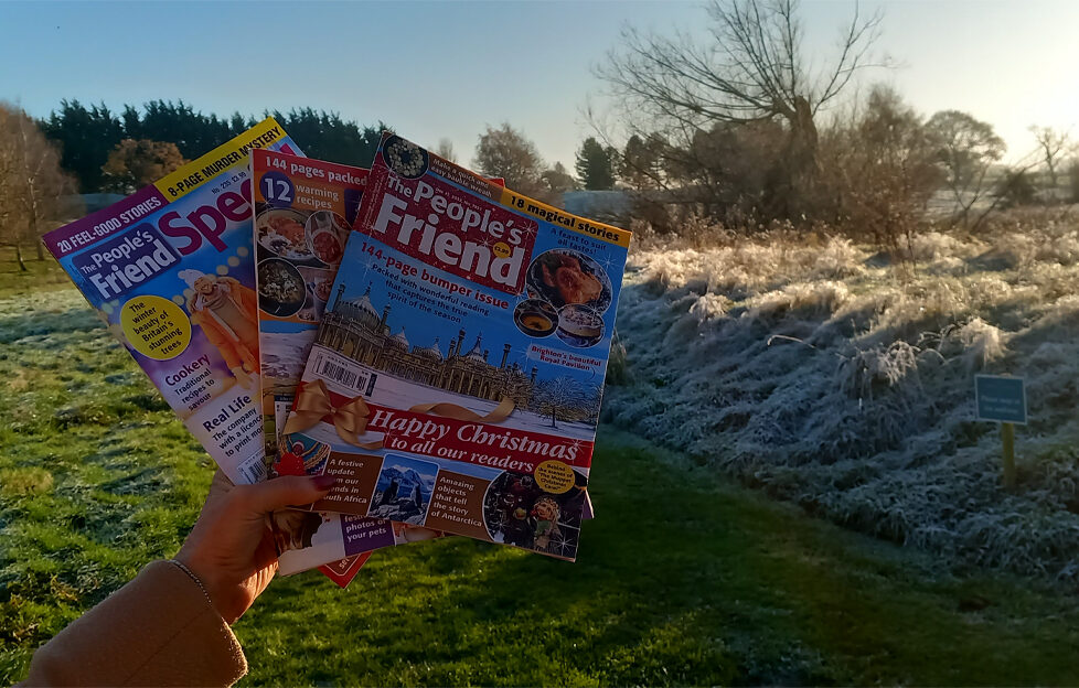 Holding The People's Friend magazine at a sunlit frosty countryside at Alvaston Hall