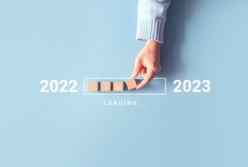 A flatlay with 2022 loading into 2023 with a hand placing blocks as a loading bar