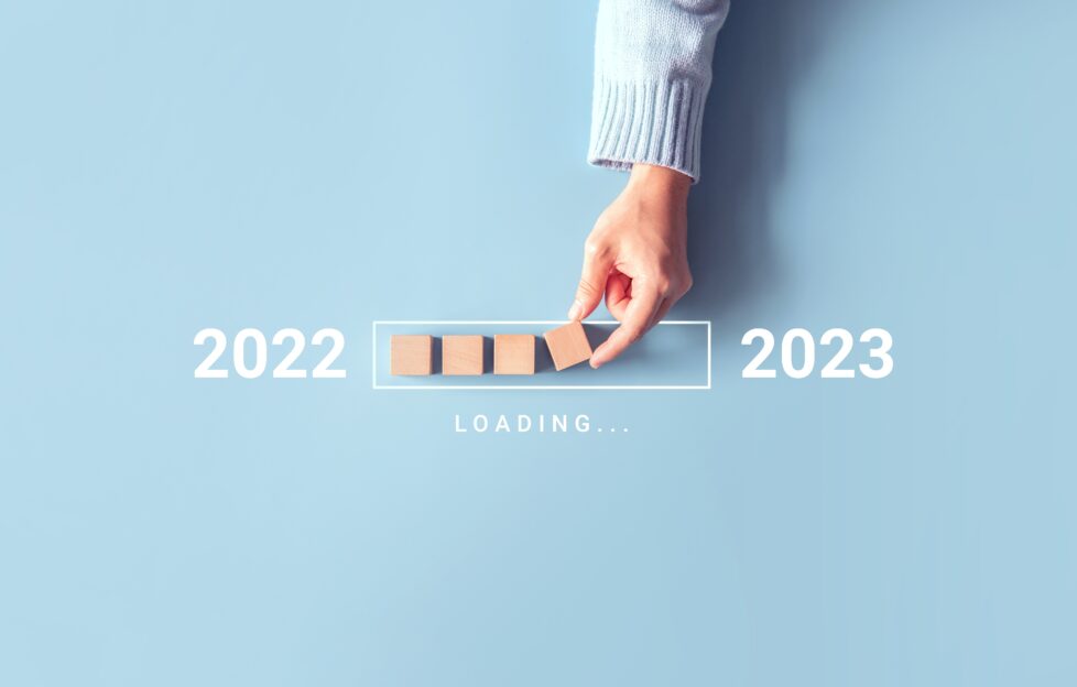 A flatlay with 2022 loading into 2023 with a hand placing blocks as a loading bar