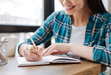 Woman smiling as she's writing in a notepad