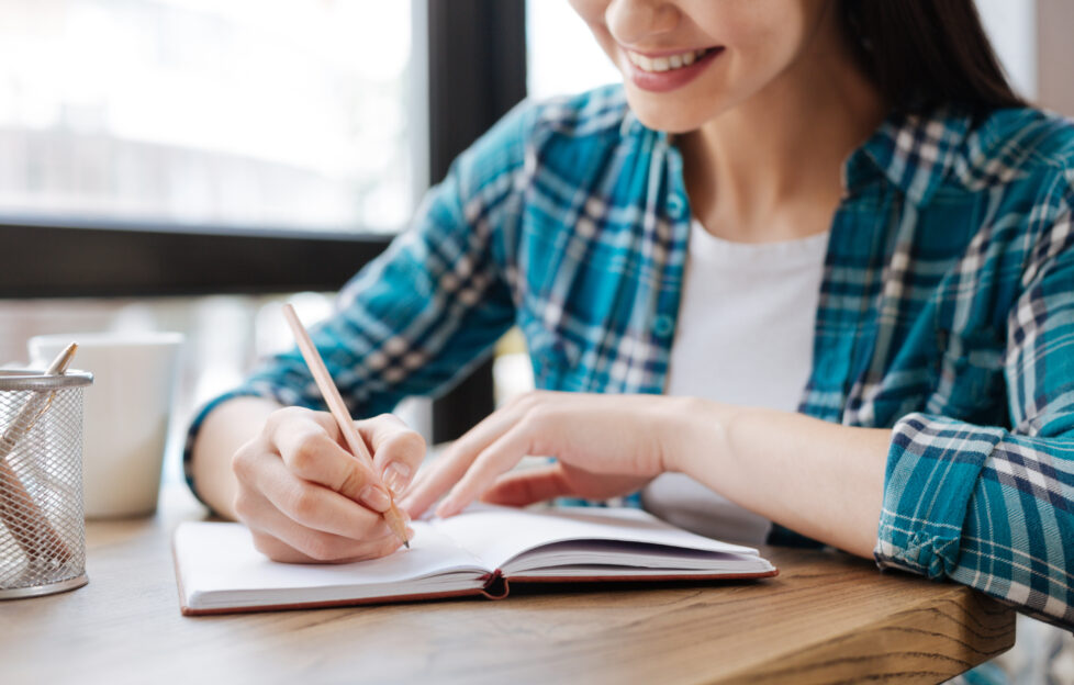 Woman smiling as she's writing in a notepad