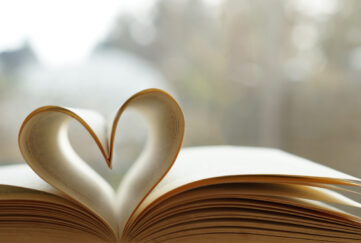 Book laid on its spine with pages folded into each other to make a heart shape