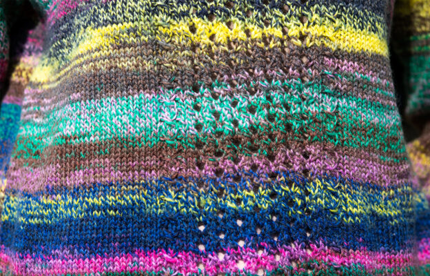 Close up of knitting pattern on a multicoloured striped sweater