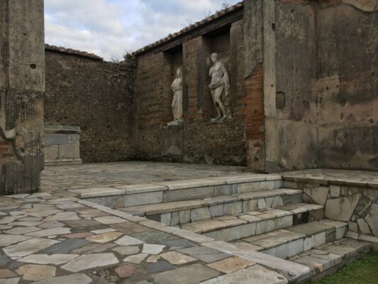 Marble steps leading up to two Roman statues at the Archaeological park of Herculaneum