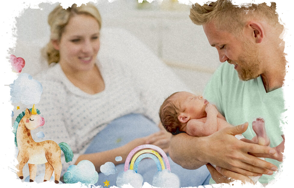 A new father holds is newborn in his arms as he looks down smiling at the baby. His wife is sitting up in her hospital bed in the background. She is wearing a hospital gown and smiling as she watches her husband enjoy a moment with his new son. The infant is just wearing a diaper as dad enjoys some skin-on-skin time.