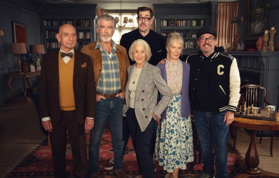 First look at 'The Thursday Murder Club Cast' dressed in character and posing on set with author Richard Osman standing behind them.