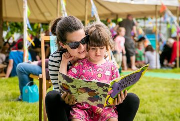 A mum and daughter reading a book at the Hay Literary Festival