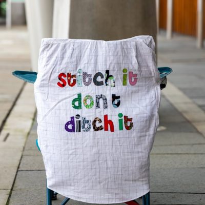 "Stitch it don't ditch it" embroidered on a sheet which is displayed on a camping chair to attract passers-by.