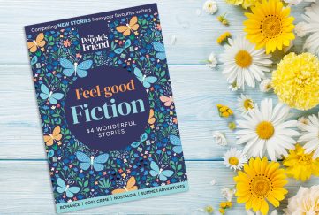 Feel Good Fiction Bookazine cover on a table with daisies