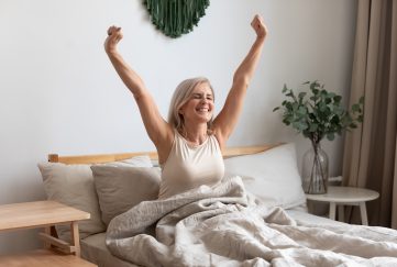 Joyful Healthy Older Woman Sitting On Bed Waking Up After Nap.