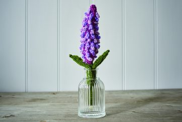 Free knitting pattern for a lilac flower bloom, shown here displayed in a vase