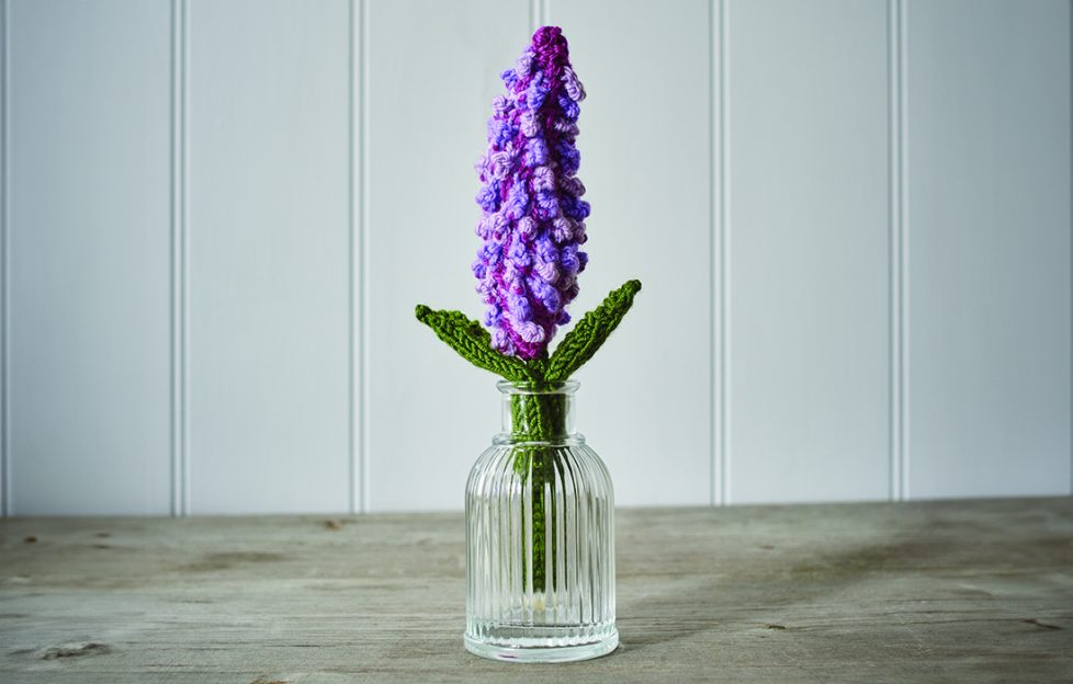 Free knitting pattern for a lilac flower bloom, shown here displayed in a vase