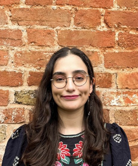 Smiling girl in her twenties with long brown hair and glasses.