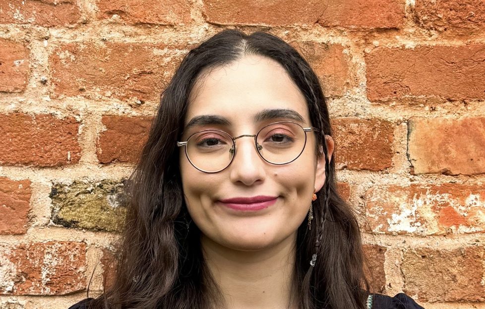 Smiling girl in her twenties with long brown hair and glasses.