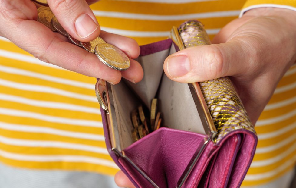 Women holding a pink purse and counting British coins into it.