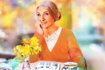 A grandmother sitting at a table with tea.