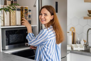 Lady loading Tupperware box into cupboard