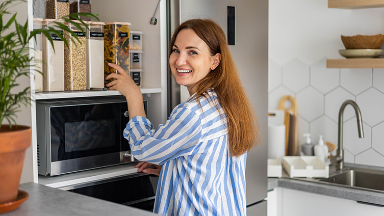 Lady loading Tupperware box into cupboard