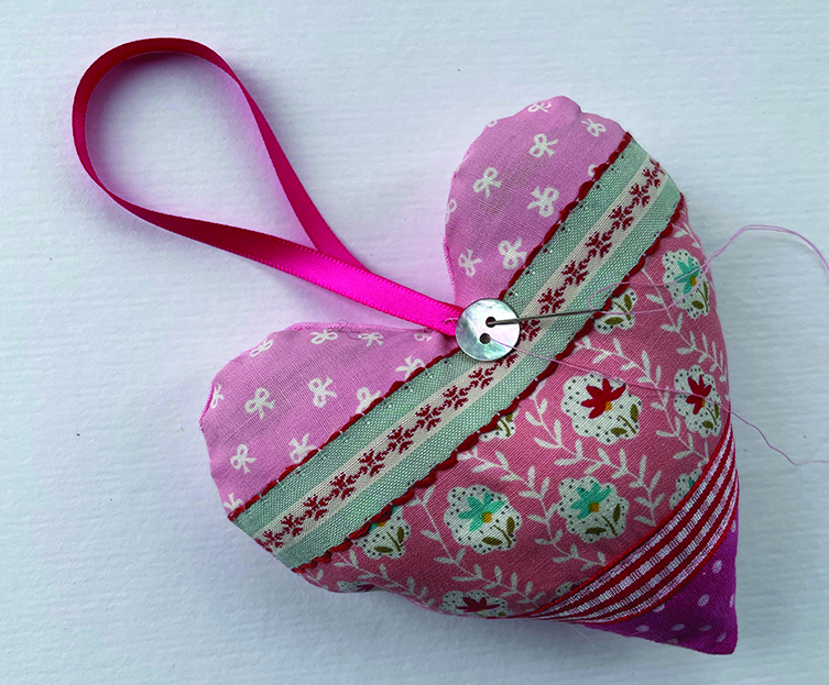 Sew a ribbon loop and button on the heart