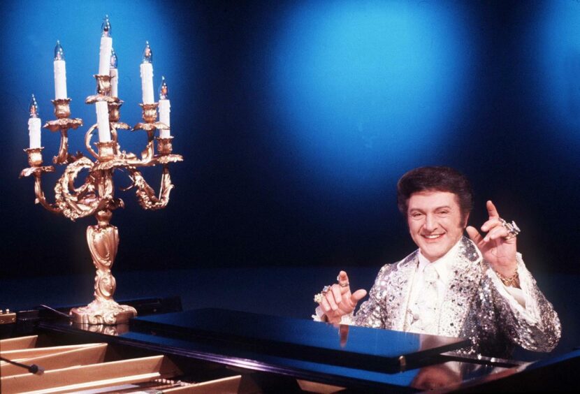 Liberace at his piano in 1978 alongside his famous candelabra. Image: Shutterstock.