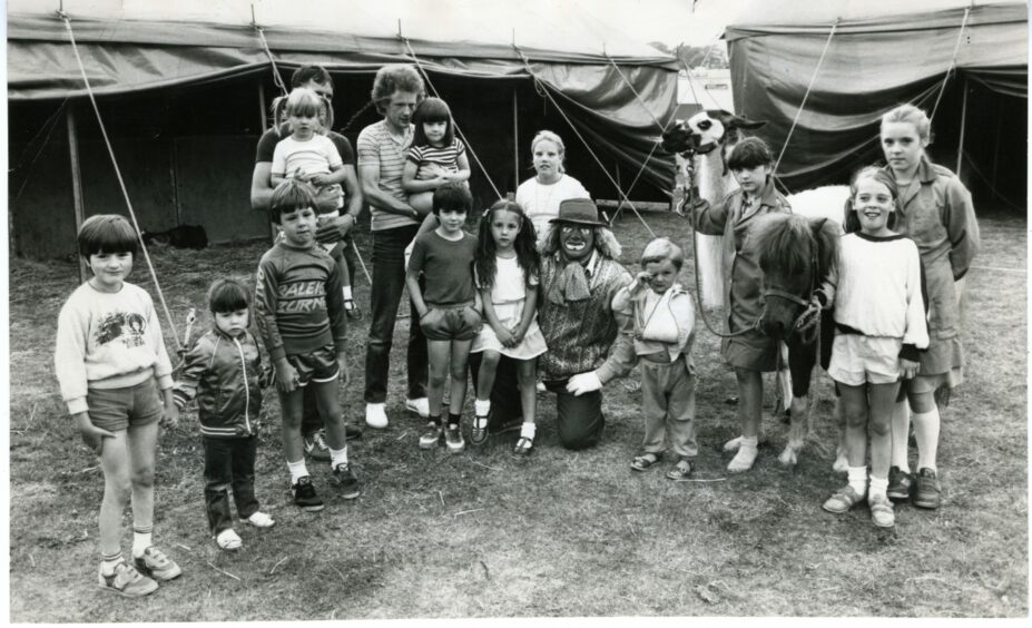 A group of children posing with Charlie the Clown at Austen Brothers' Circus.