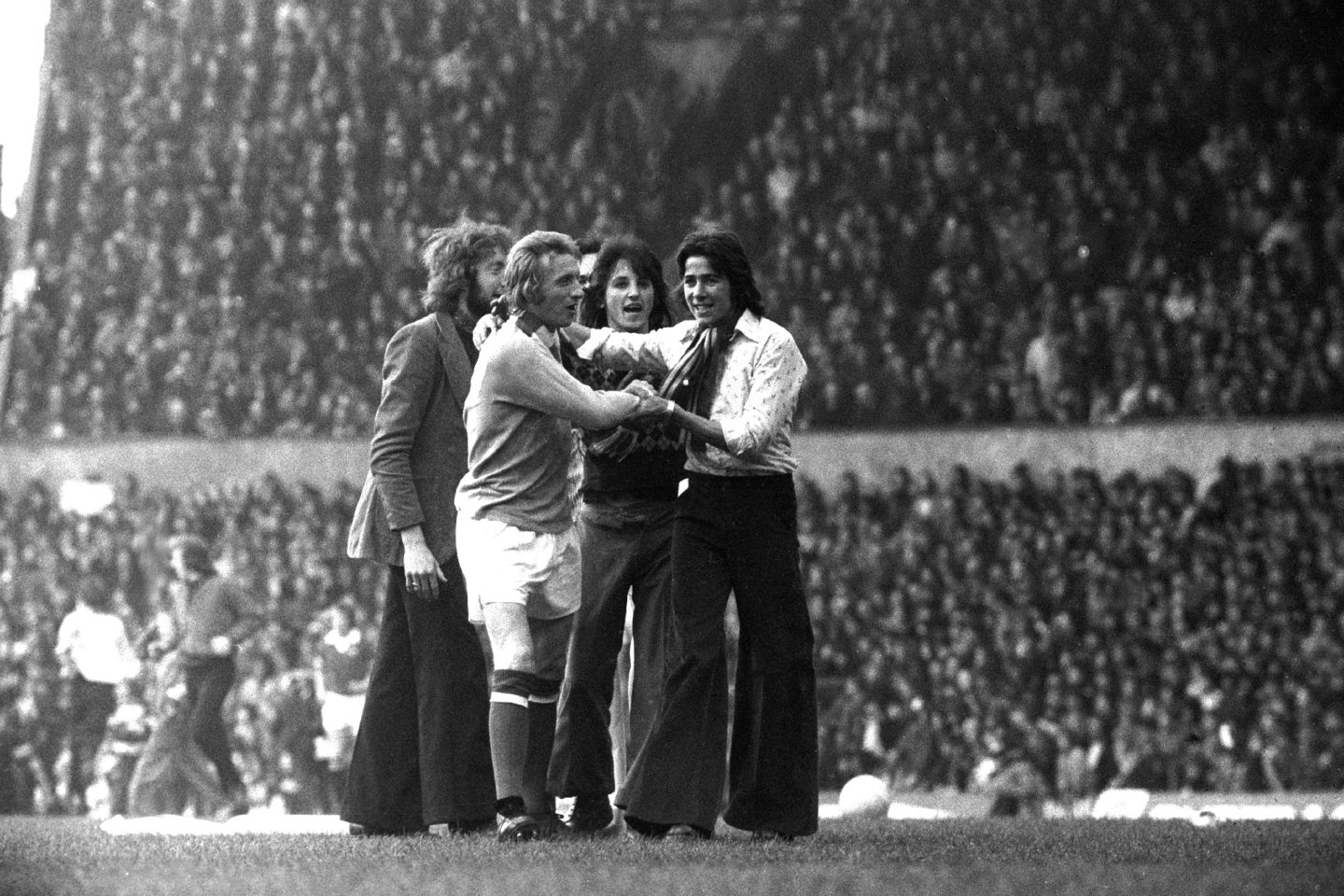Manchester United fans wrap United scarves around the neck of Manchester City's Denis Law, who had just scored the winning goal with a cheeky backheel to condemn United, his former club, to relegation in 1974.