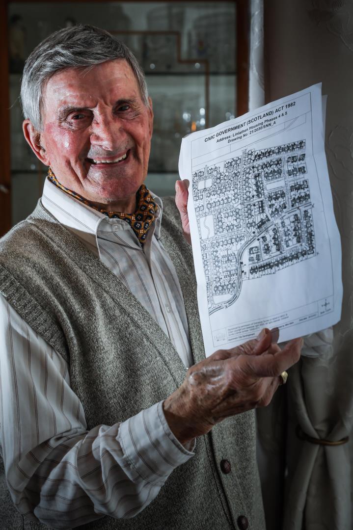 Peter Schiavetta smiling and holding up the plans for the Ben Attow memorial street names 