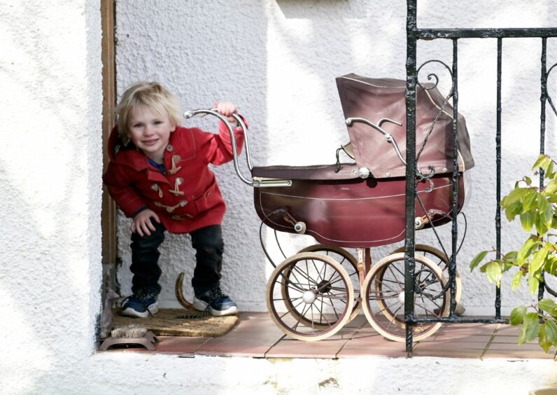 Playing with the pram is Caroline's great-nephew, three-year-old Magnus. Sandy McCook