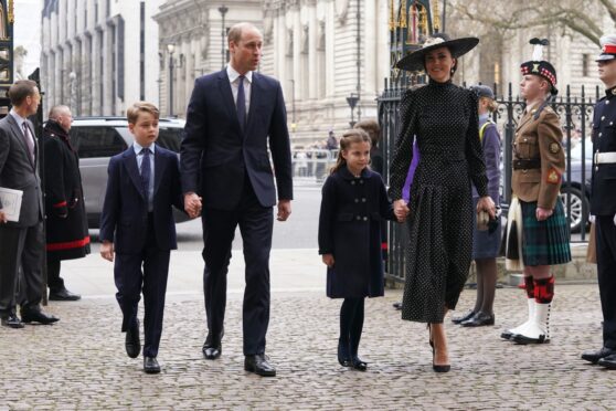 The Duke of Cambridge walking holding Prince George by the hand, and the Duchess of Cambridge walking holding Princess Charlotte by hand.