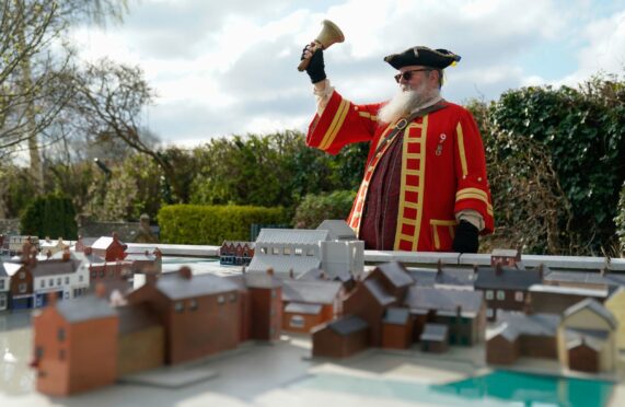 Chris Brown, the Town Crier and Mayor's Serjeant of Wimborne Minster, rings his bell as he looks over new 'model of a model' which has been created at Wimborne Model Town in Dorset to celebrate the charity attraction's 70th anniversary season, ahead of their re-opening on April 2. The new mini-model, which is 1/10th the size of the existing miniature buildings, has been laid out next to the existing model and includes shops, banks, pubs, the Minster and the King's Head Hotel. Andrew Matthews/PA Wire.