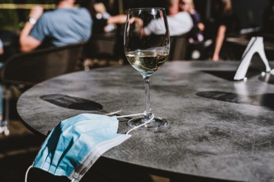 Those visiting hospitality venues must continue to wear face masks for a 'further short period' in enclosed spaces, such as restaurants, bars and cafes.