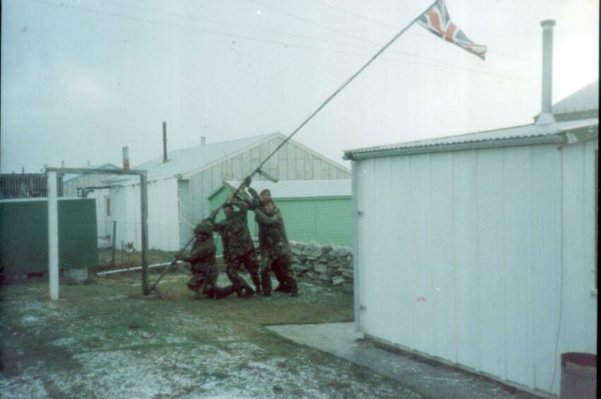 Troops raising the flag on the liberation of the Falkland Islands.  ANL/Shutterstock.