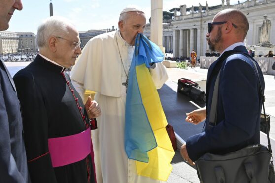 Pope Francis kisses a Ukrainian flag during his weekly General Audience in Saint Peter's Square, Vatican City. Ansa/Press Office Vatican Media/Shutterstock.