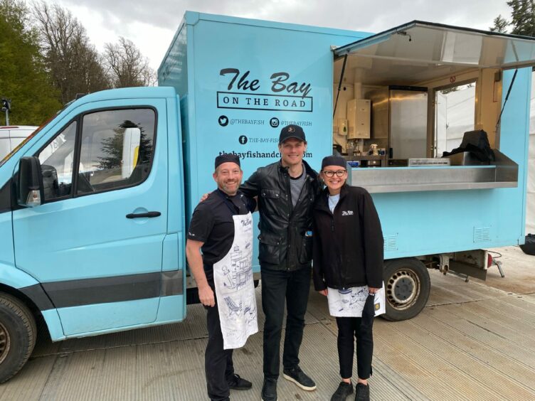 Calum and Viktorija Richardson, with Outlander star Sam Heughan centre, in front of their food van 